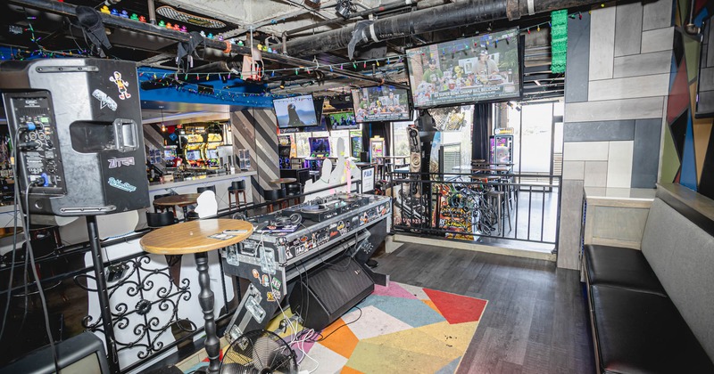 Entertainment area with bar, DJ equipment and table, and TV screens