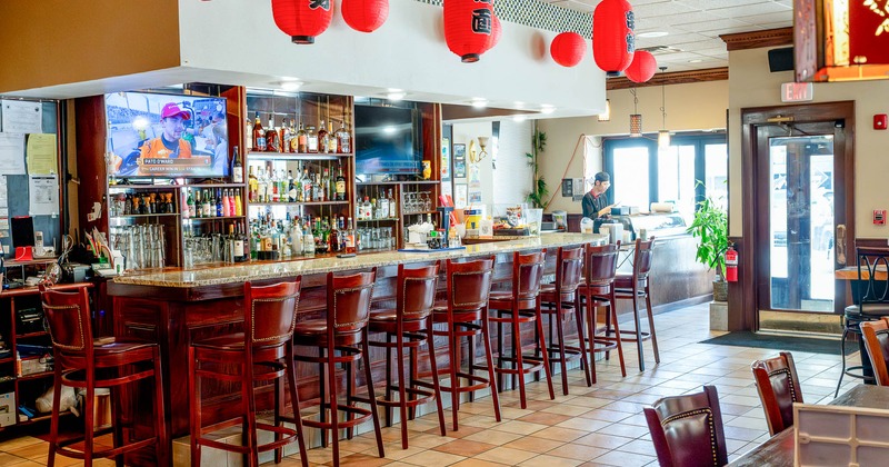 Interior of a restaurant bar with red lanterns and high-back bar stools