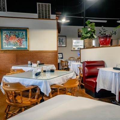 Interior with red booths, wooden chairs, set tables and wall decorations.