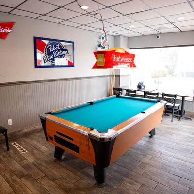 Interior with a pool table,  Budweiser light fixture, and beer signs on the wall.