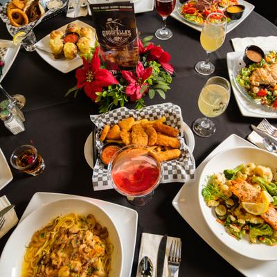 Various drinks and meals served on the table with a flower arrangement.