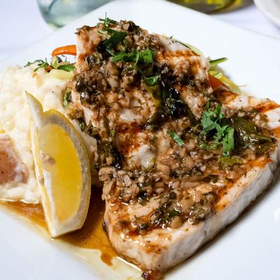 Swordfish filet served with mashed potatoes and a lemon wedge for garnish.