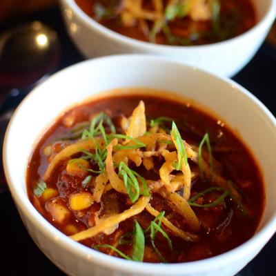 Stew with smoked BBQ chicken, sweet corn, and lima beans served in two bowls.