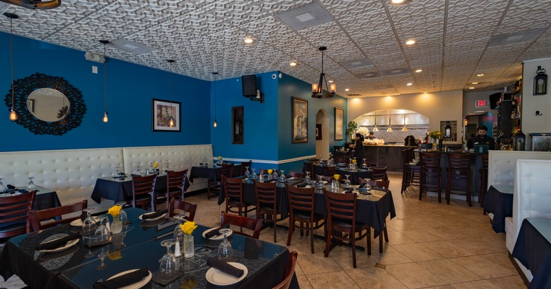 A modern interior - blue walls, white patterned ceiling, and neatly arranged dining tables