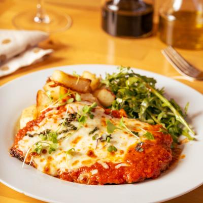 Eggplant Parmigiana served with roasted potatoes and a fresh arugula salad.