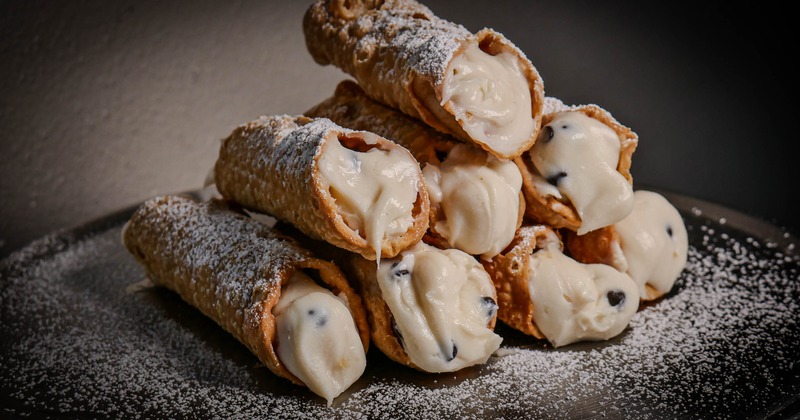 Cannoli dessert with ricotta cream filling, chocolate chips, and powdered sugar