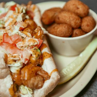 Shrimp po' boy sandwich served with hush puppies.