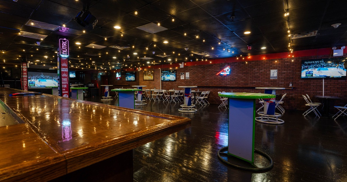 Interior - a wooden countertop, brick walls, string lights and multiple TVs showing a sports game