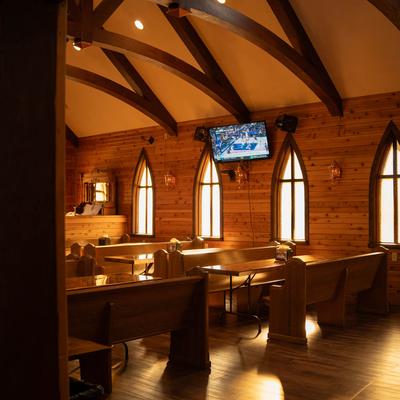 Interior design featuring wooden walls and furniture, ceiling arched beams, and arched windows.