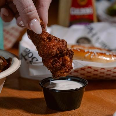 Hand dipping a chicken wing into ranch sauce.