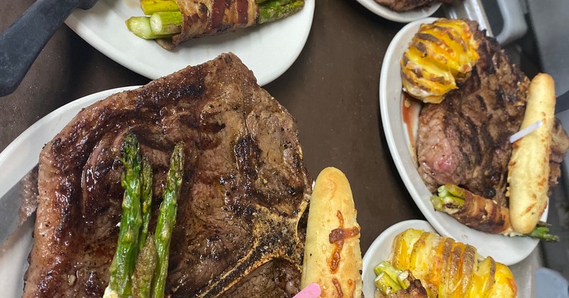 Several plates of grilled steaks with various sides