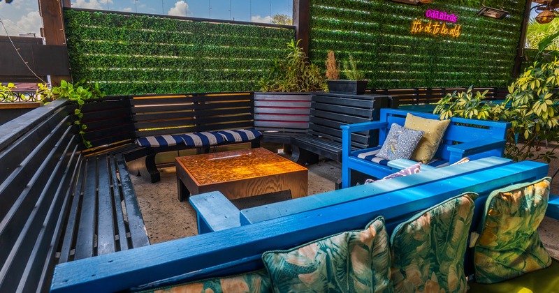 Exterior, patio, lounge area, benches with colorful pillows, artificial grass wall