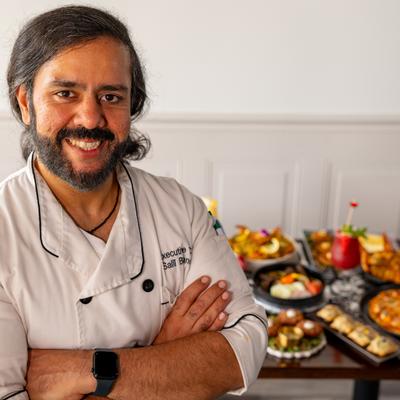 Chef posing for a shot with a table full of dishes in the background.