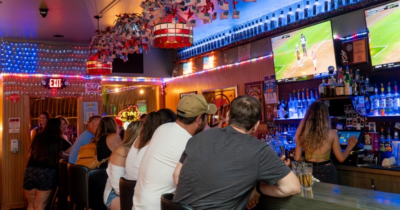 Party on a bar, tv screen above people