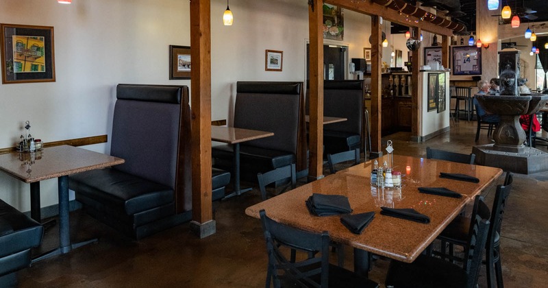 Interior, seating area, booths with tables, marble table in the middle, fountain in the back