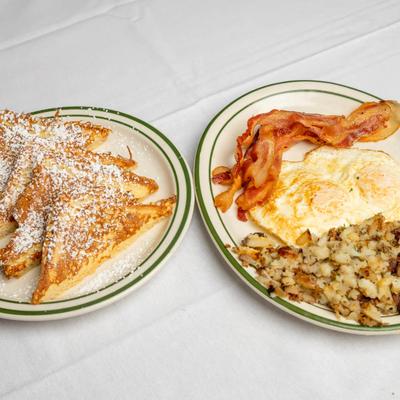 French toast dusted with powdered sugar served with fried eggs, bacon, and hash browns.