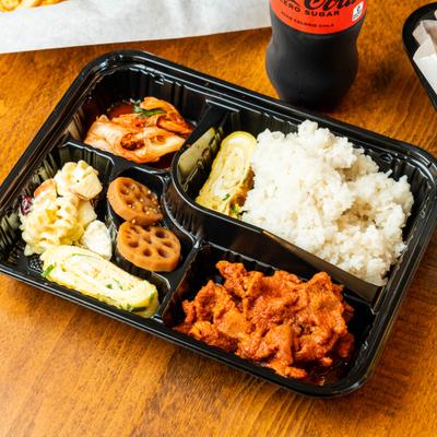 Korean bento box with spicy pork, portion of steamed rice, and various traditional side dishes.