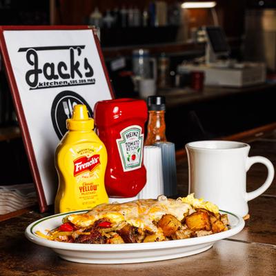 Breakfast plate with eggs, potatoes, and peppers beside condiments and coffee at Jack’s Kitchen.