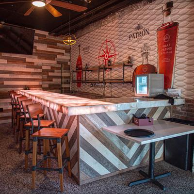 Modern rustic bar featuring glowing countertops, wooden chevron panels, and Patron branding.