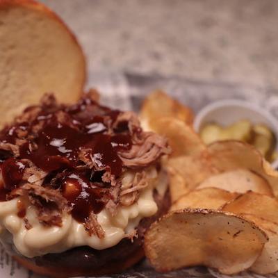 Boss Hog, pulled pork sandwich served with chips and pickle.