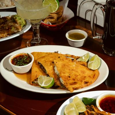 Jumbo Quesabirria served with consome and lime wedges.