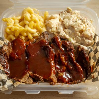 Tri-tip served with sides of potato salad and mac and cheese, top view.