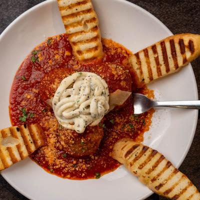 Meatballs in tomato sauce, with ricotta cheese, parmesan, and toasted baguette.