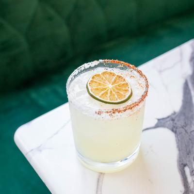 Margarita on the rocks with salted and spiced rim and a lime wheel.