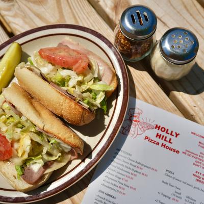 Two cold-cut sandwiches with lettuce and tomato, served with grated cheese and paper flakes.