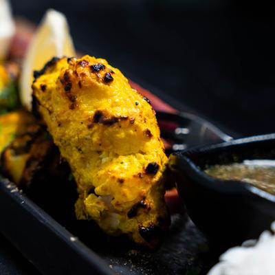Fish tikka pieces on black platter.