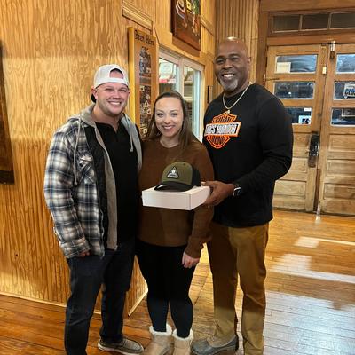 Three people posing for a photo in a rustic venue with wooden floors.