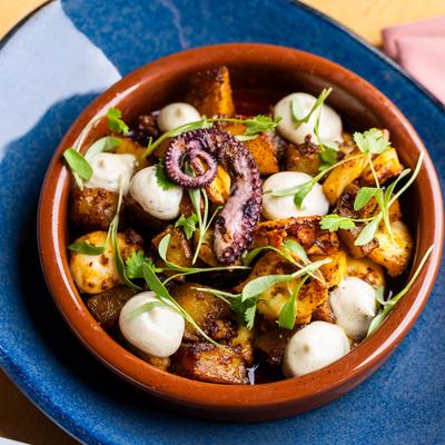 Octopus and roasted potatoes with herbs and dollops of creamy sauce.