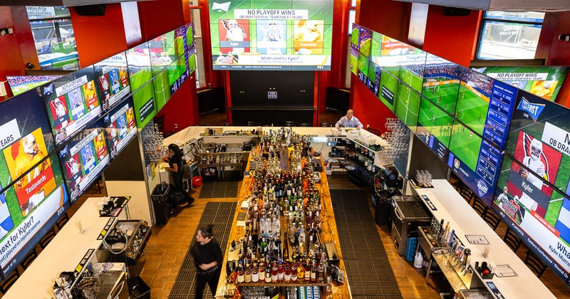 High-angle view of a sports bar with a large central island bar and TVs
