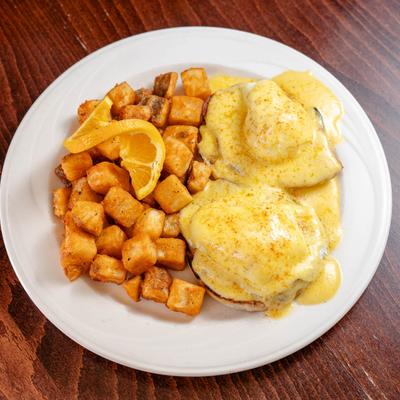 Eggs benedict served with potato fries.