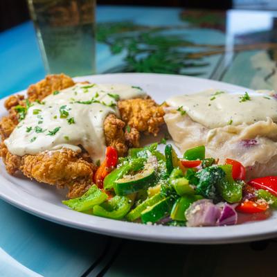 Country fried steak, with gravy, mashed potatoes, and veggies.