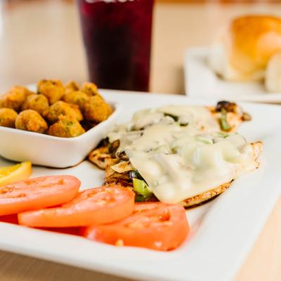 Grilled chicken breast topped with Swiss cheese, served with fried okra and sliced tomatoes.
