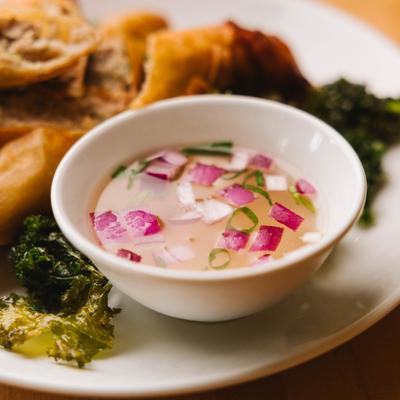 Dipping sauce with diced onions and herbs, served with spring rolls.