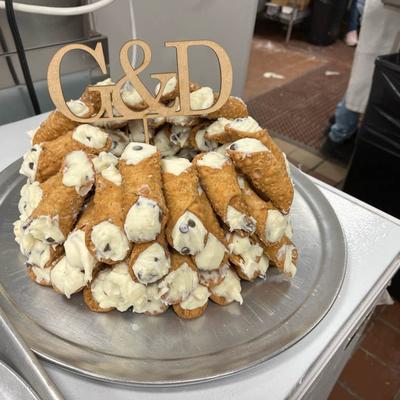Large arrangement of cannoli served on a metal tray.