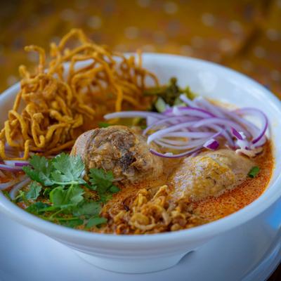 Noodle soup with chicken drumstick in homemade yellow curry.