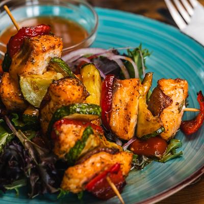 Salmon kebab skewers served with salad and a dipping sauce.