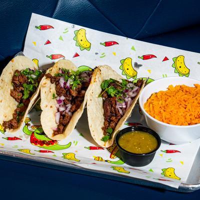 Steak tacos with dipping sauce and a bowl of Mexican rice.