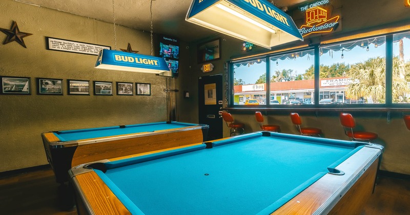 Interior, pool tables with high chairs and wall table in the back