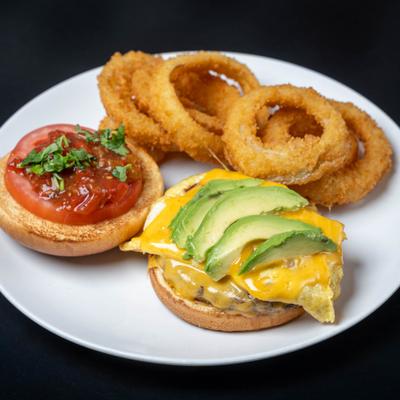 Coronado Burger topped with melted cheese and avocado, served with onion rings.