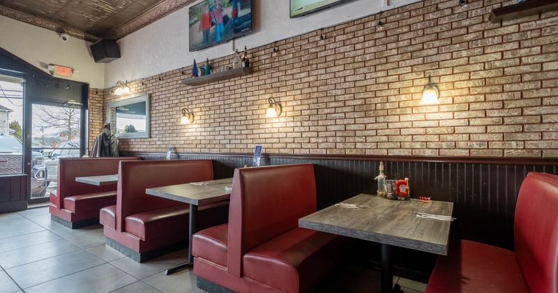 Interior with red booths, brick walls and televisions mounted above.
