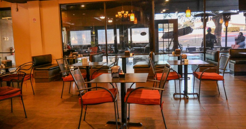 Indoor dining area with tables, chairs, and large windows