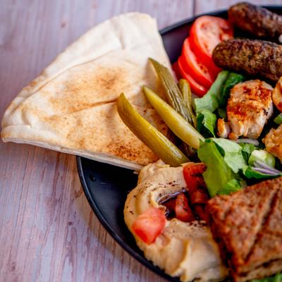 Mixed grill platter with salad, hummus and pita, close-up.