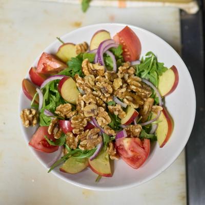 Fresh salad with greens, walnuts, red onion, apples, and tomatoes.