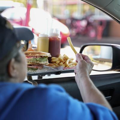 customer eating from tray of food at their car.