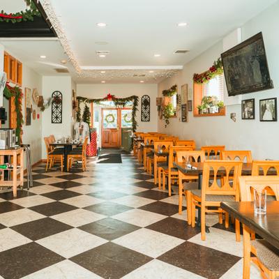 Restaurant interior with tables, chairs, wall decorations and checkered floor.