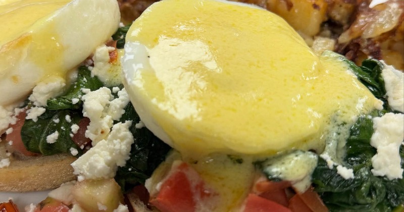 Greek Style Benedict served with home fries and slice of orange